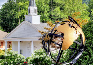 An outdoor picture of a globe in the foreground and a white chapel in the background.