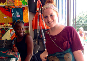 A young black woman and a young white woman smile inside a retail shop in Mozambique.