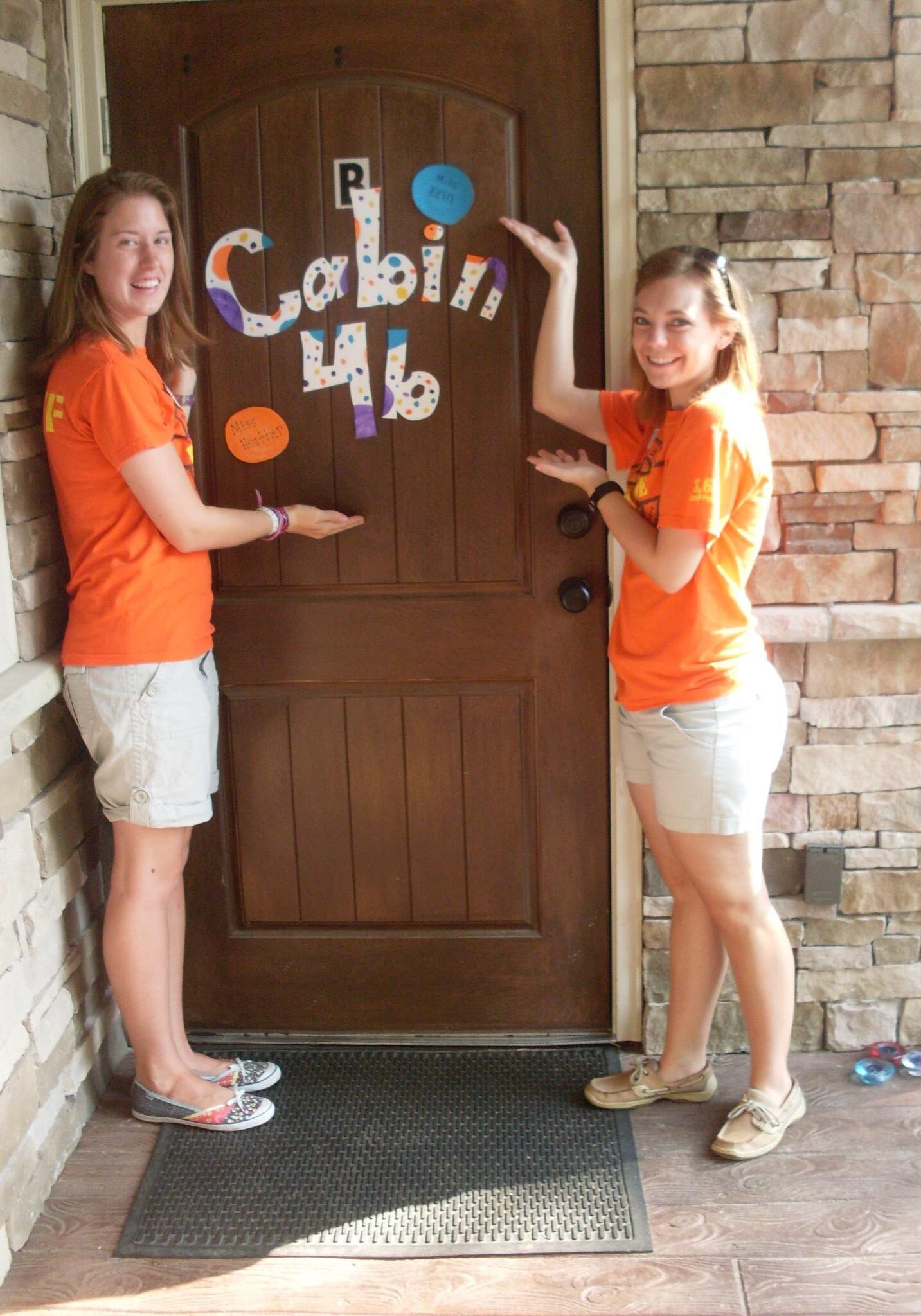 Two summer camp cabin leaders standing by the entrance of their cabin.