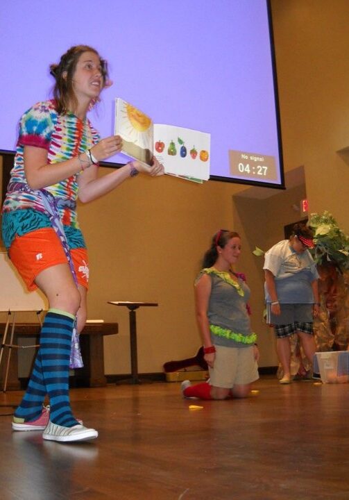 Camp leader narrates a story during a performance event at summer camp.