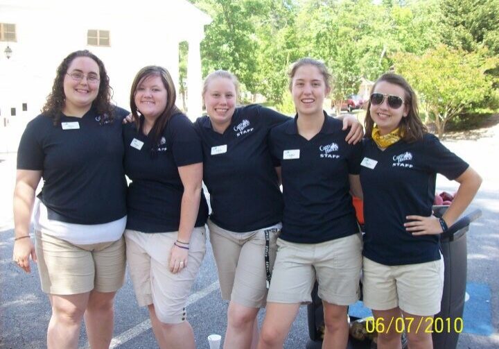 Group of summer camp support staff pose outside in their staff shirts.
